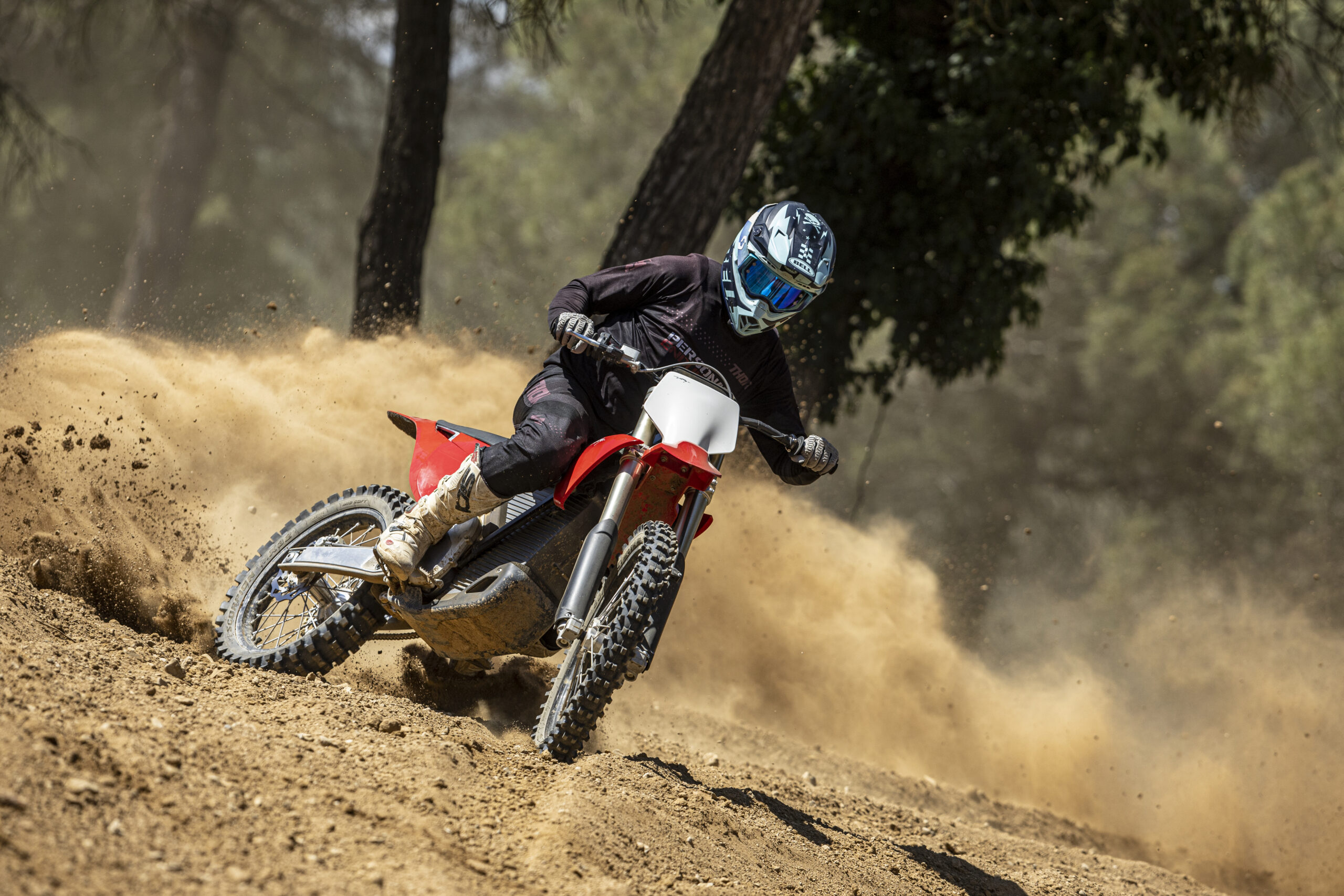 Piloto con una Stark Varg levantando una nube de tierra en un tramo de motocross